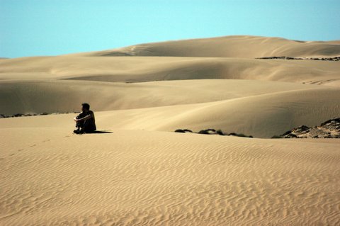 Isolation - man sitting alone in the desert